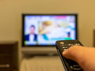 Person pressing button on TV remote